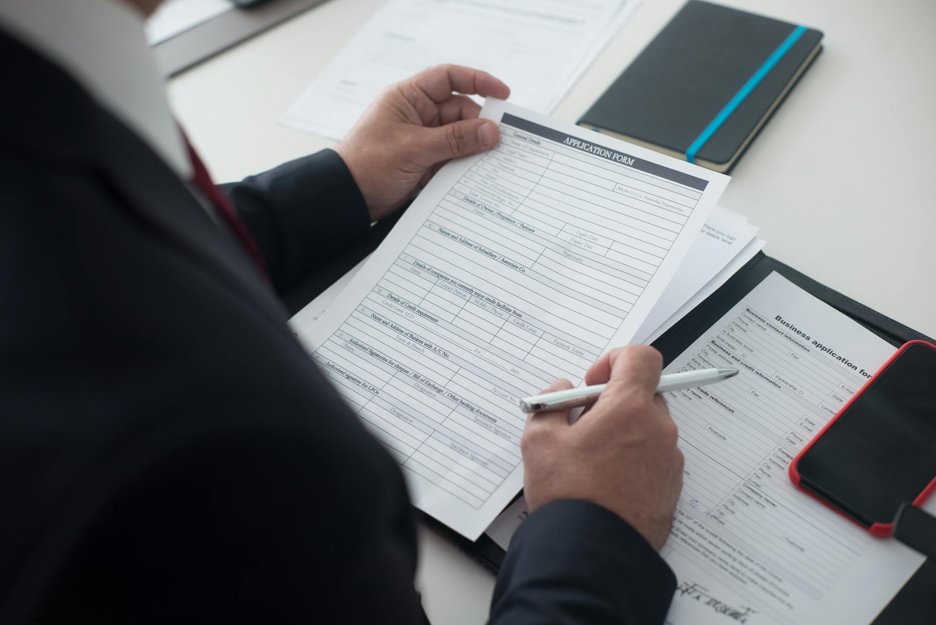 Rekruter w garniturze analizuje papierowy formularz aplikacyjny